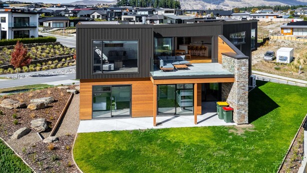 A modern two-story house with large windows, a stone fireplace, and a well-maintained lawn. - Grand Alpine Vista Escape (Wanaka)