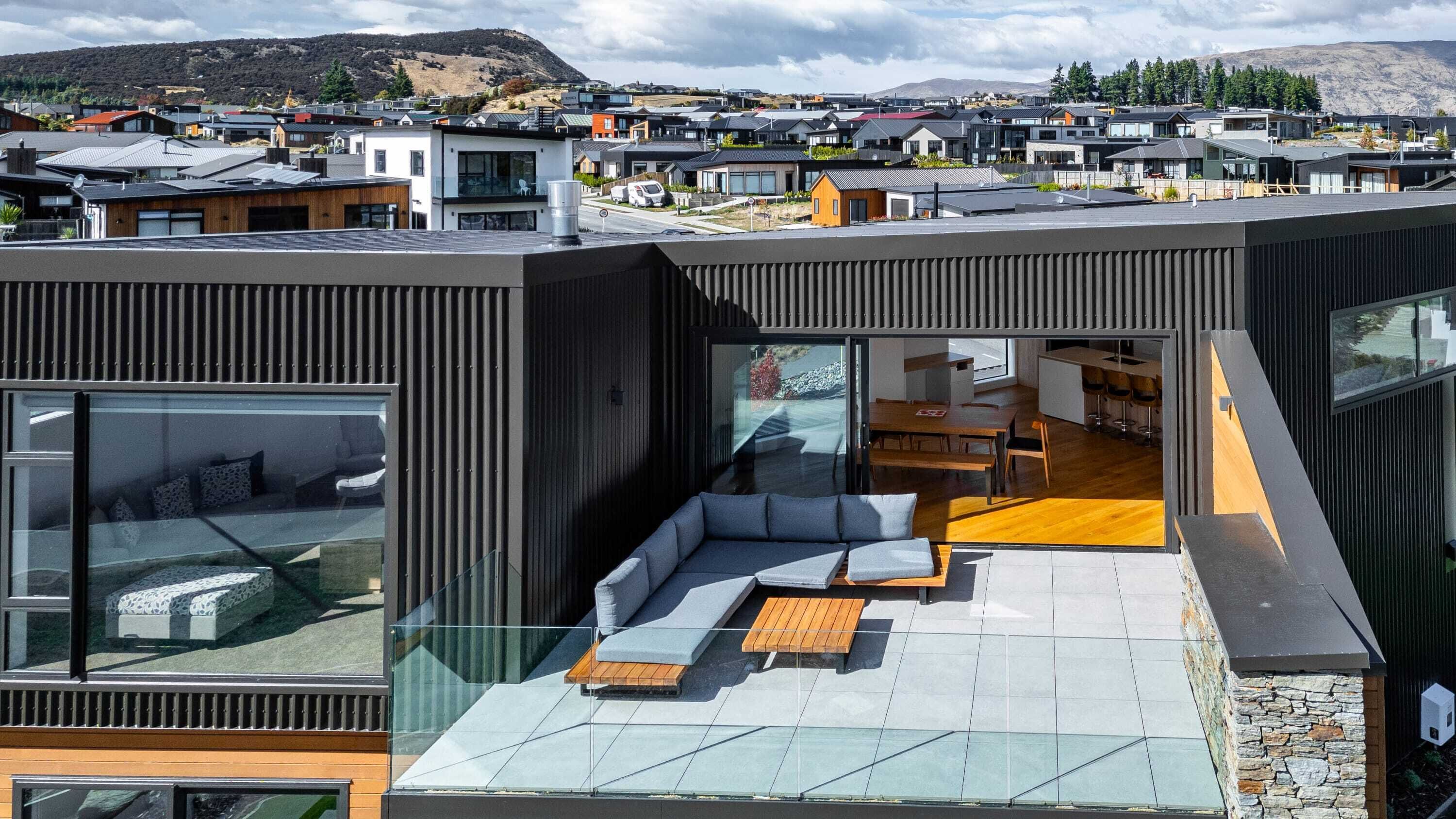 Ein modernes Wohngebäude mit Dachterrasse, ausgestattet mit einer Sitzecke und einem Essbereich.