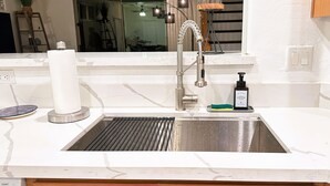 Een moderne keuken met een roestvrijstalen spoelbak, een papieren handdoekdispenser en een zeepdispenser.