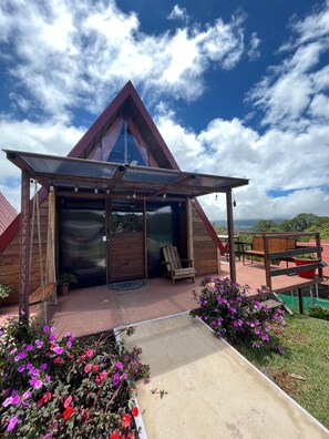A modern, triangular wooden building with a covered porch and a large glass door.