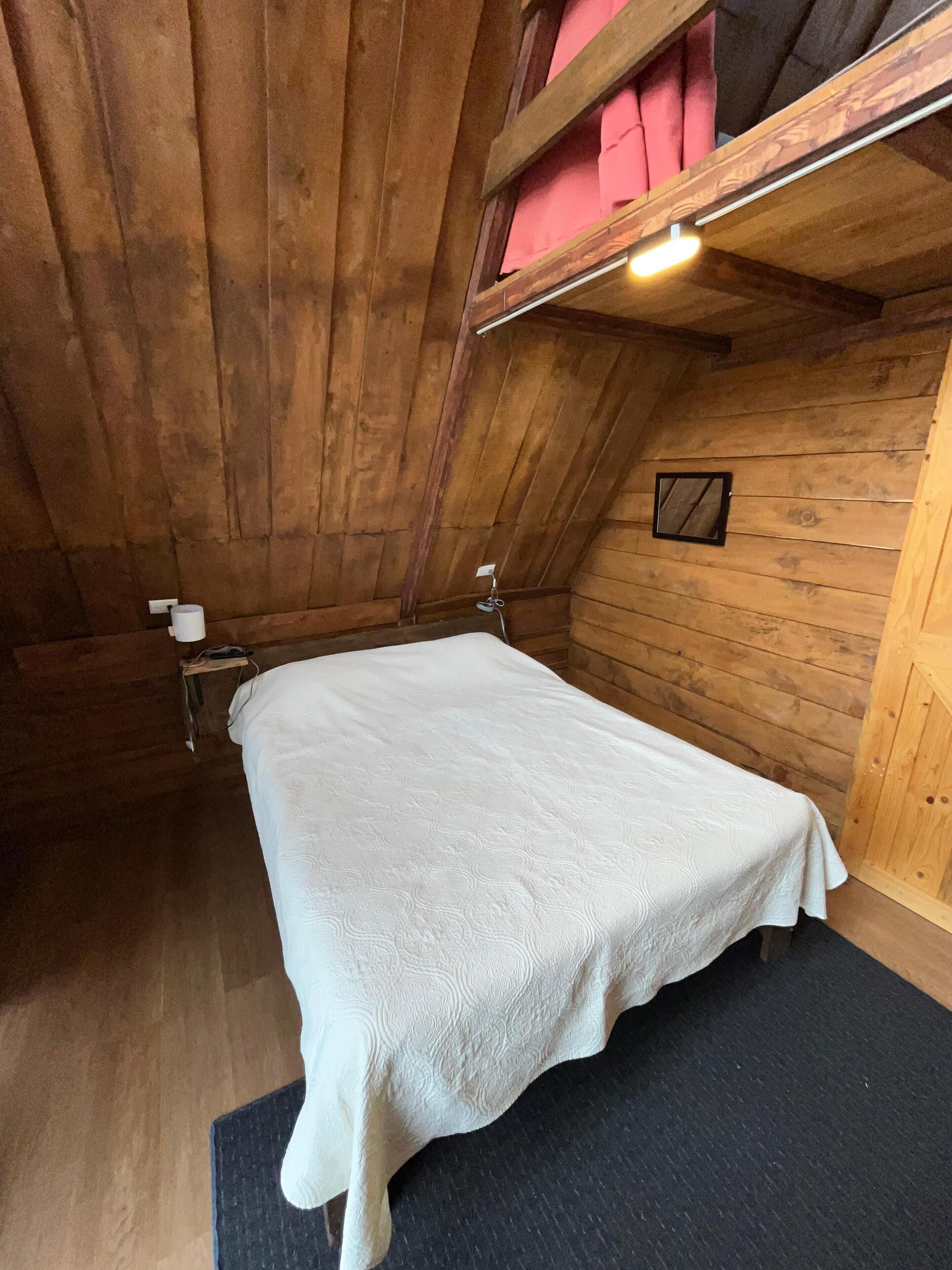 A small, cozy room with wooden walls and a single bed.