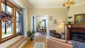 A living room with a fireplace, a sofa, and a dining area in the background. - Family/Pet Friendly Craftsman (Newberg)