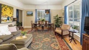A living room with a sofa, a coffee table, a dining table with chairs, a patterned rug, and a television. - Family/Pet Friendly Craftsman (Newberg)