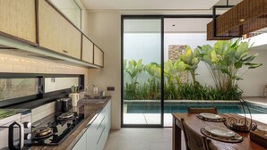 Una cocina moderna con una isla grande, un comedor con vista a una piscina y un puerta corrediza de vidrio que da a un balcón.