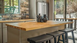 Una cocina con una isla grande, electrodomésticos de acero inoxidable y vistas al exterior.