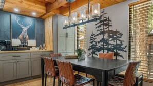 Una cocina moderna con comedor, que cuenta con una gran mesa de madera, sillas de cuero y una lámpara fijada a la pared.