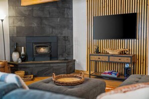 Una sala de estar acogedora con chimenea, un televisor de pantalla plana montado en una pared de madera y un espacio de descanso confortable.
