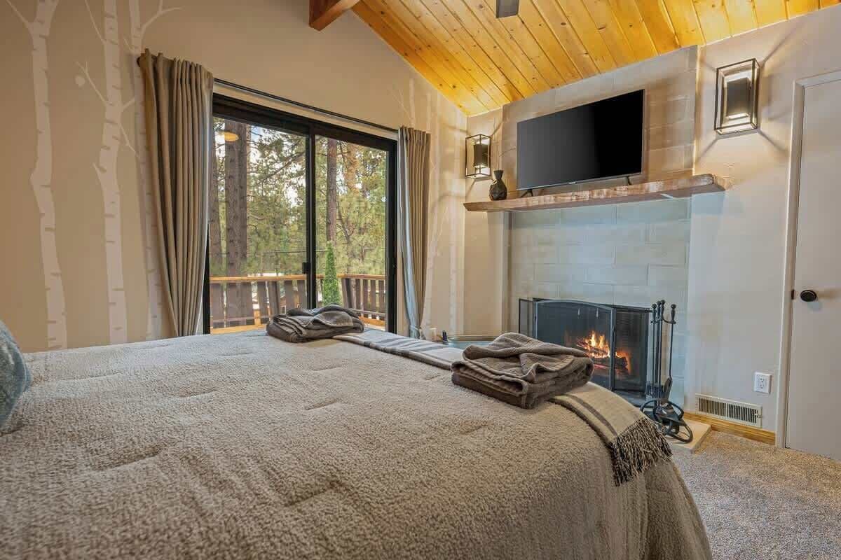 Un dormitorio acogedor con una cama grande, una chimenea y un televisor montado encima.