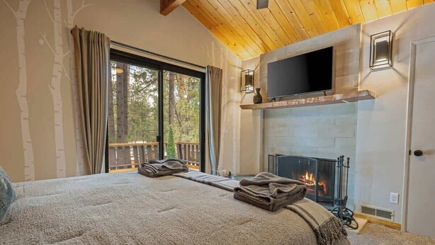 Un dormitorio acogedor con una cama grande, una chimenea y un televisor montado encima.