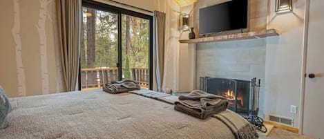 Un dormitorio acogedor con una cama grande, una chimenea y un televisor montado encima.
