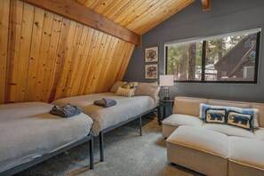 Una habitación acogedora con dos camas, un sofá y una ventana que da a una cabaña.
