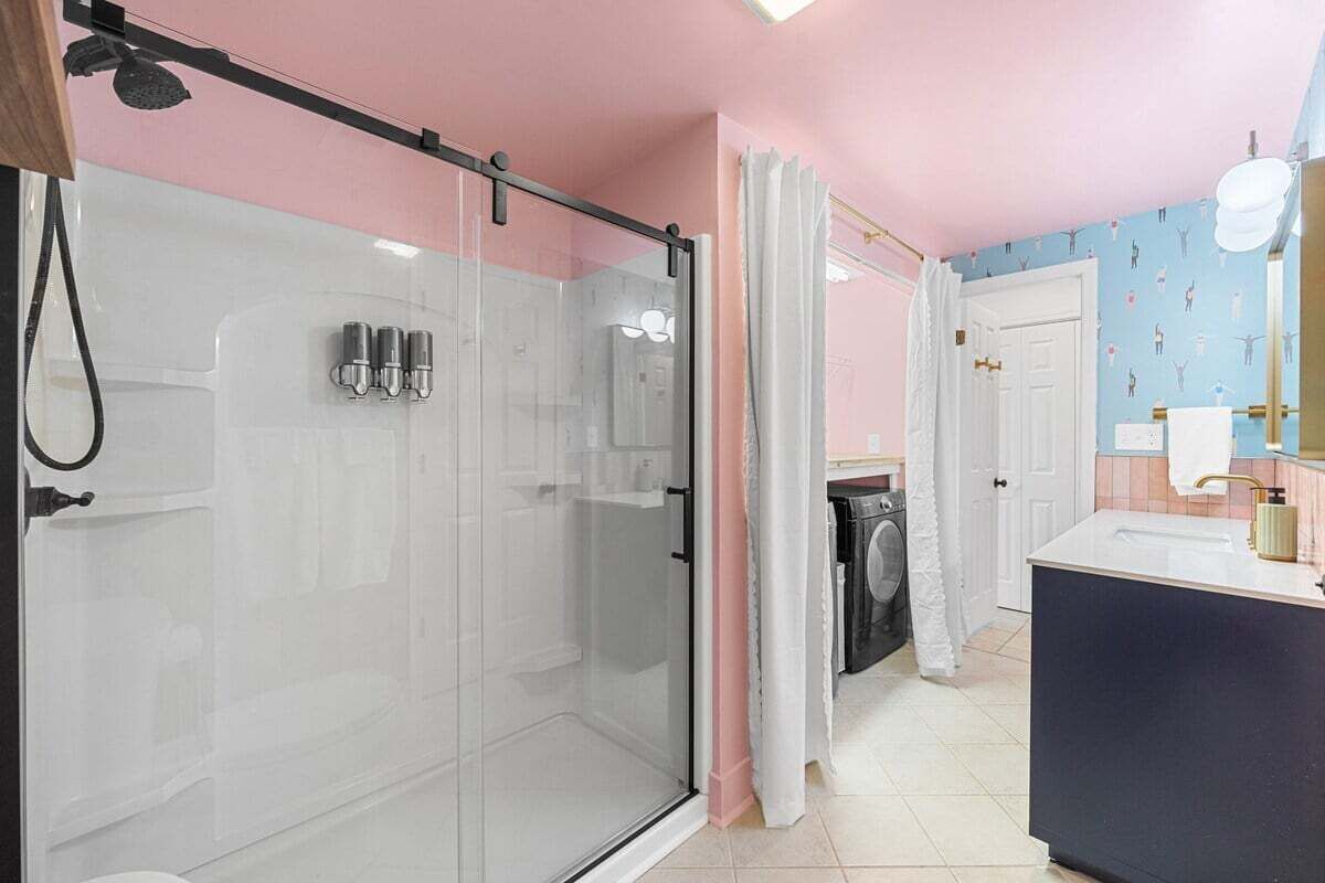 A bathroom with a glass-enclosed shower, a white sink, and a mirror.