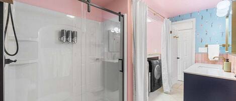 A bathroom with a glass-enclosed shower, a white sink, and a mirror.