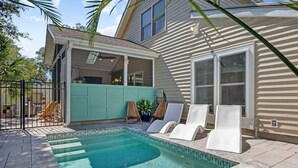 A backyard with a swimming pool, a covered patio, and a house with a garage. - Modern 4BR w/ Heated Pool | It's Always Sunny (North Myrtle Beach)