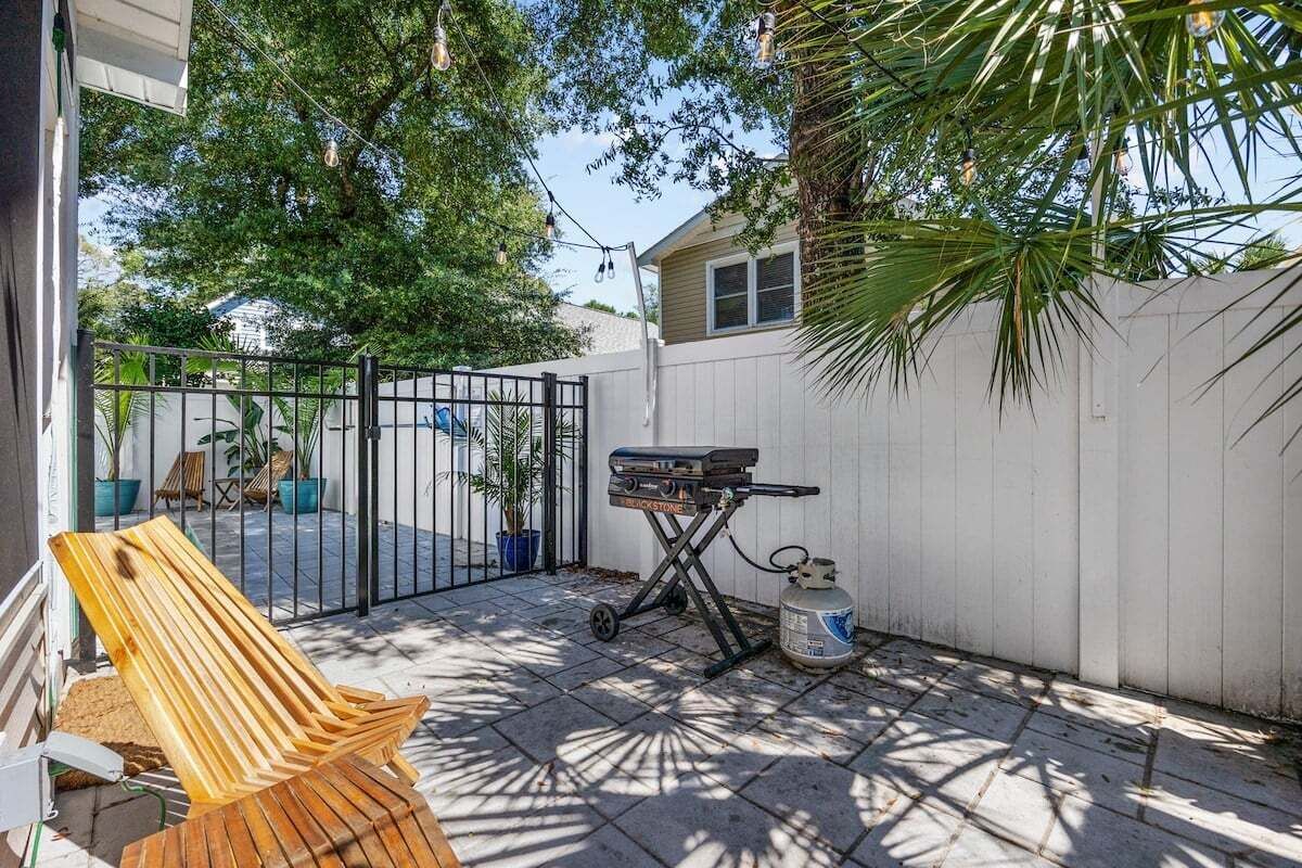 A patio with a wooden chair, a grill, and a gas canister.