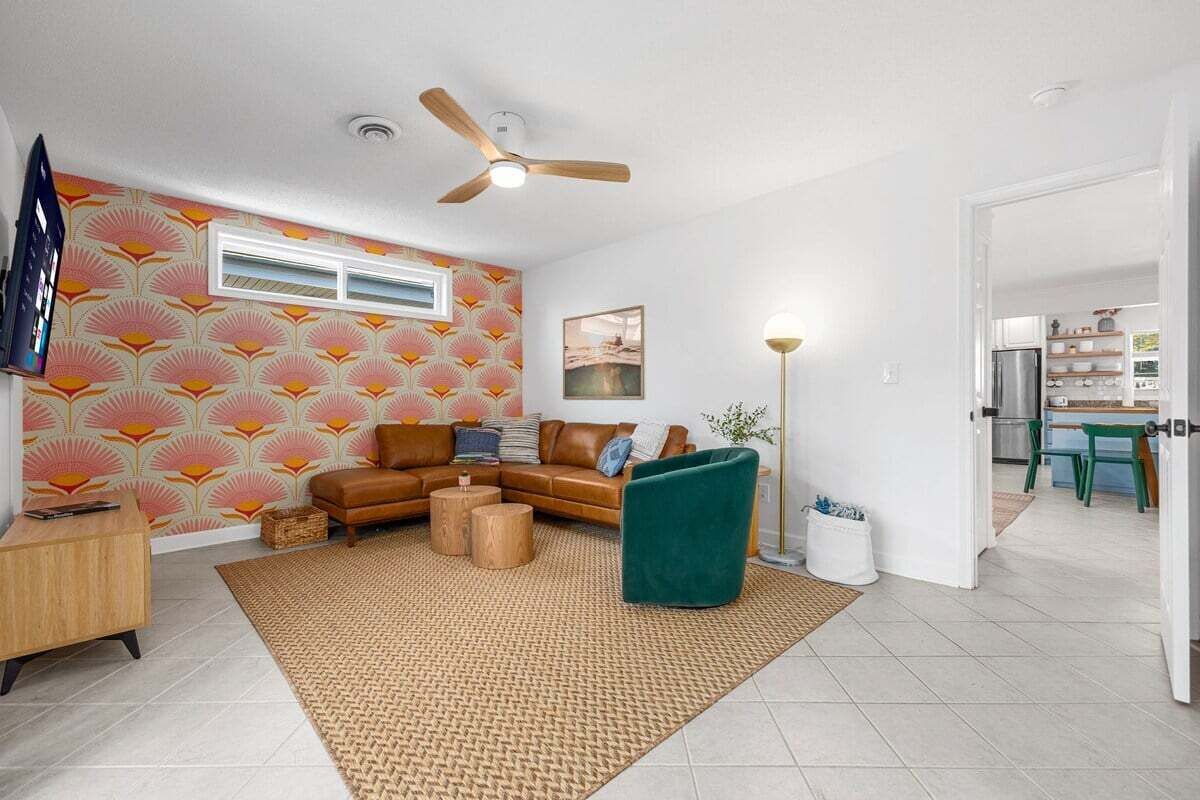 Una sala de estar con un sofá, una mesa de centro, una lámpara de pie y un ventilador de techo.