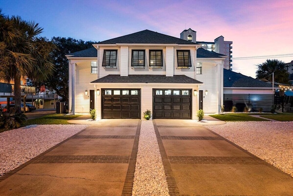A two-story house with a garage, driveway, and a well-maintained lawn.