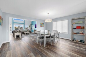 A dining area with a table and chairs, a hanging light fixture, and a bookshelf. - Kokomo | 4BR Waterfront Home w/ Rooftop Lookout (North Myrtle Beach)
