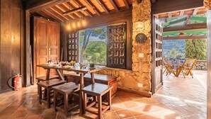 A rustic dining area with wooden tables and chairs, a stone wall, and a view of the outdoors. - Residenza Capo Perla - Capo Perla 2 (Capoliveri)