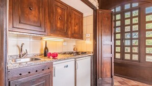 A kitchen with wooden cabinets, a stainless steel sink, a stove, and a dishwasher. - Residenza Capo Perla - Capo Perla 2 (Capoliveri)