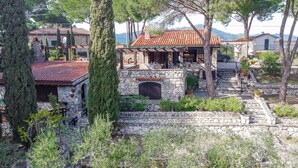 A stone building with a tiled roof, a stone archway, and a stone staircase leading up to a porch. - Residenza Capo Perla - Capo Perla 2 (Capoliveri)