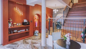 Un interior moderno con paredes de madera, suelo de mármol, una escalera y un comedor con mesa y sillas.