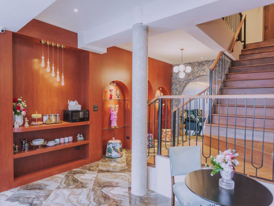 Un interior moderno con paredes de madera, suelo de mármol, una escalera y un comedor con mesa y sillas.