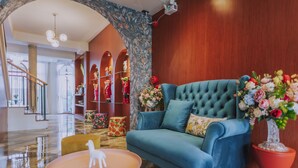 Una sala de estar moderna con un sofá color turquesa, una mesita redonda con una figurita blanca y un arreglo floral llamativo.