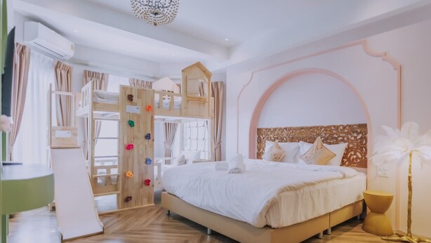 Un dormitorio con literas, una casita de juegos de madera y un amplio ventanal de arco.