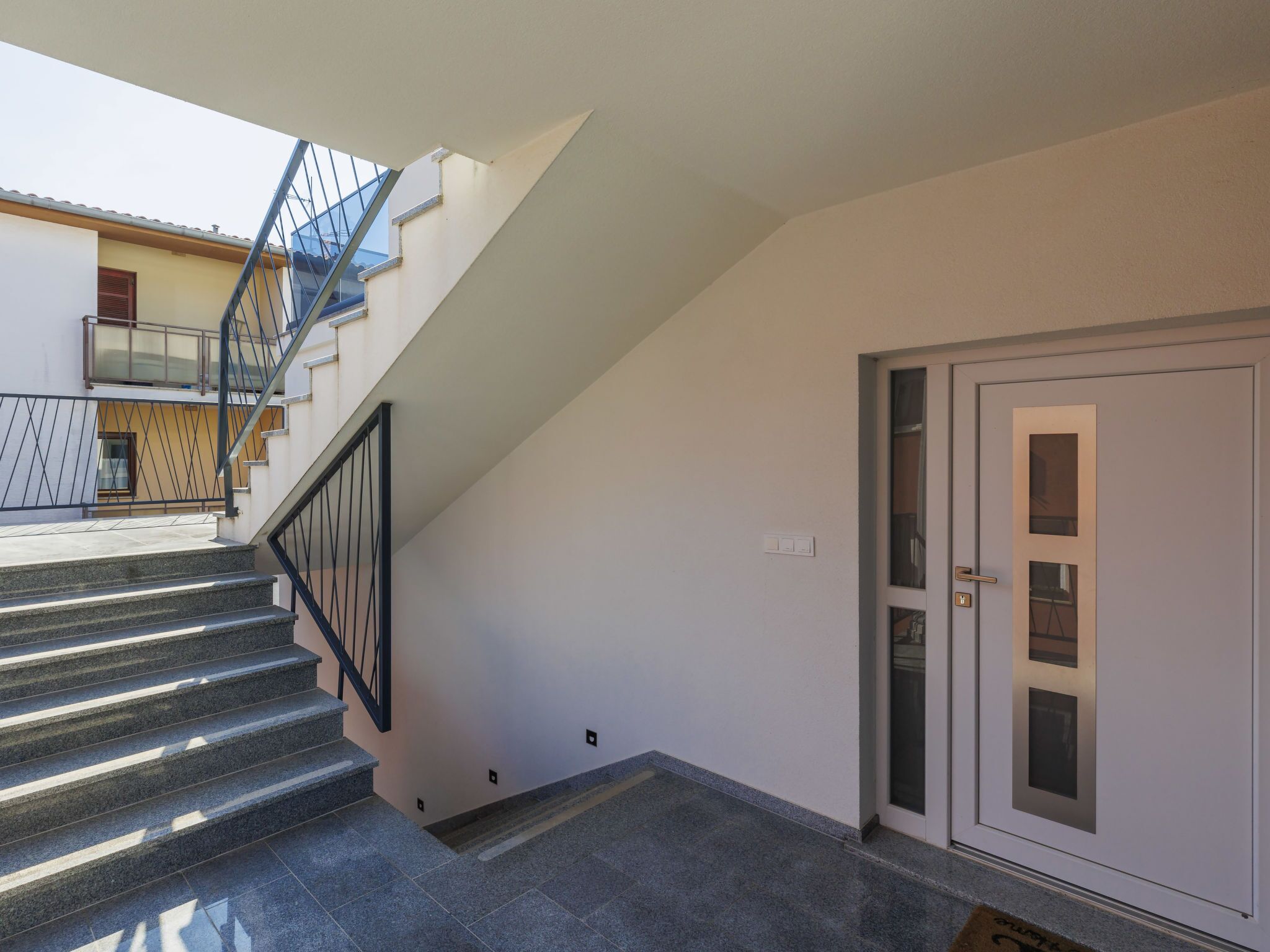 Un escalier menant à un palier avec une porte et une fenêtre.