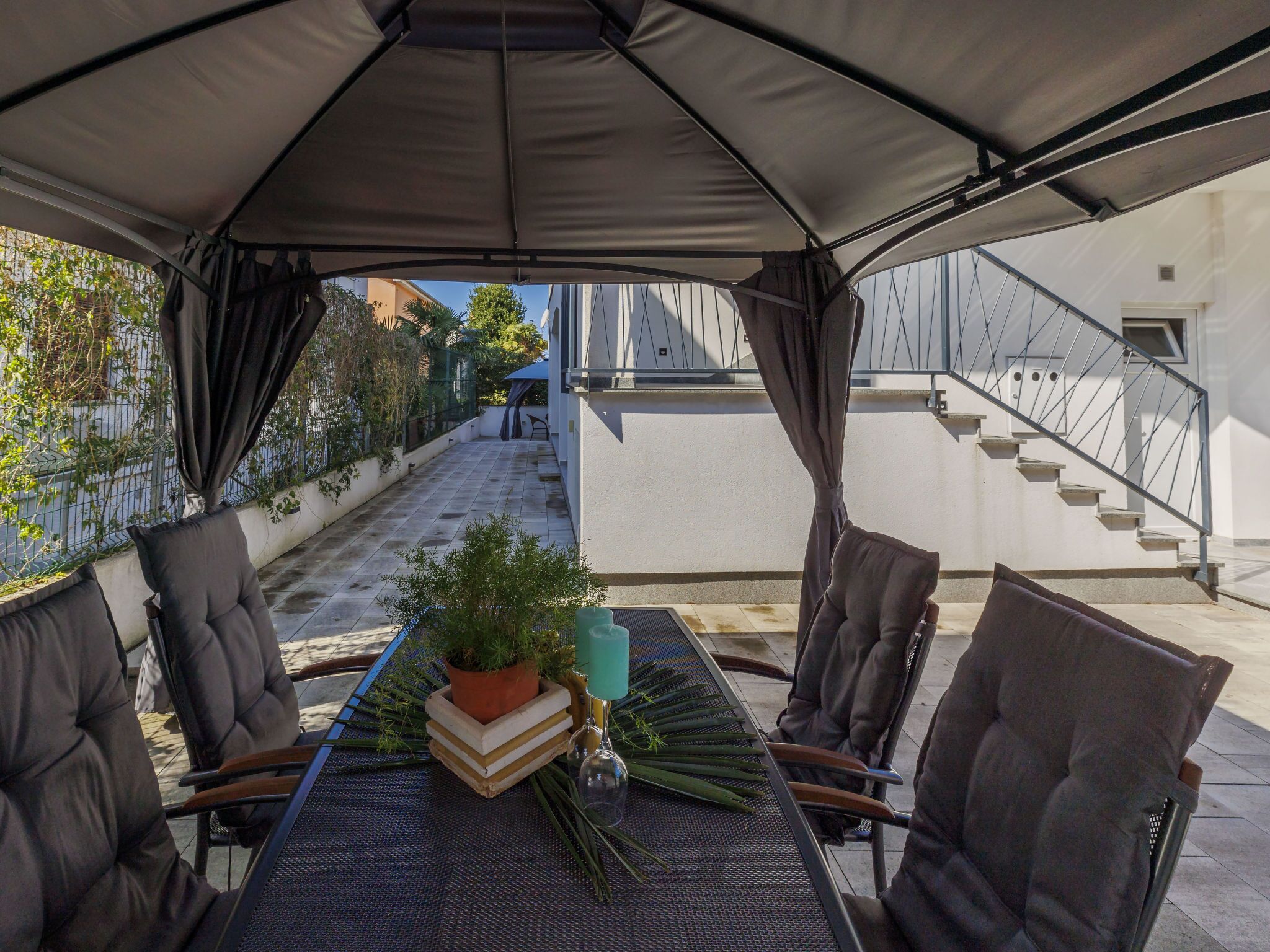 Une terrasse extérieure avec une table, des chaises et un pot de fleurs.