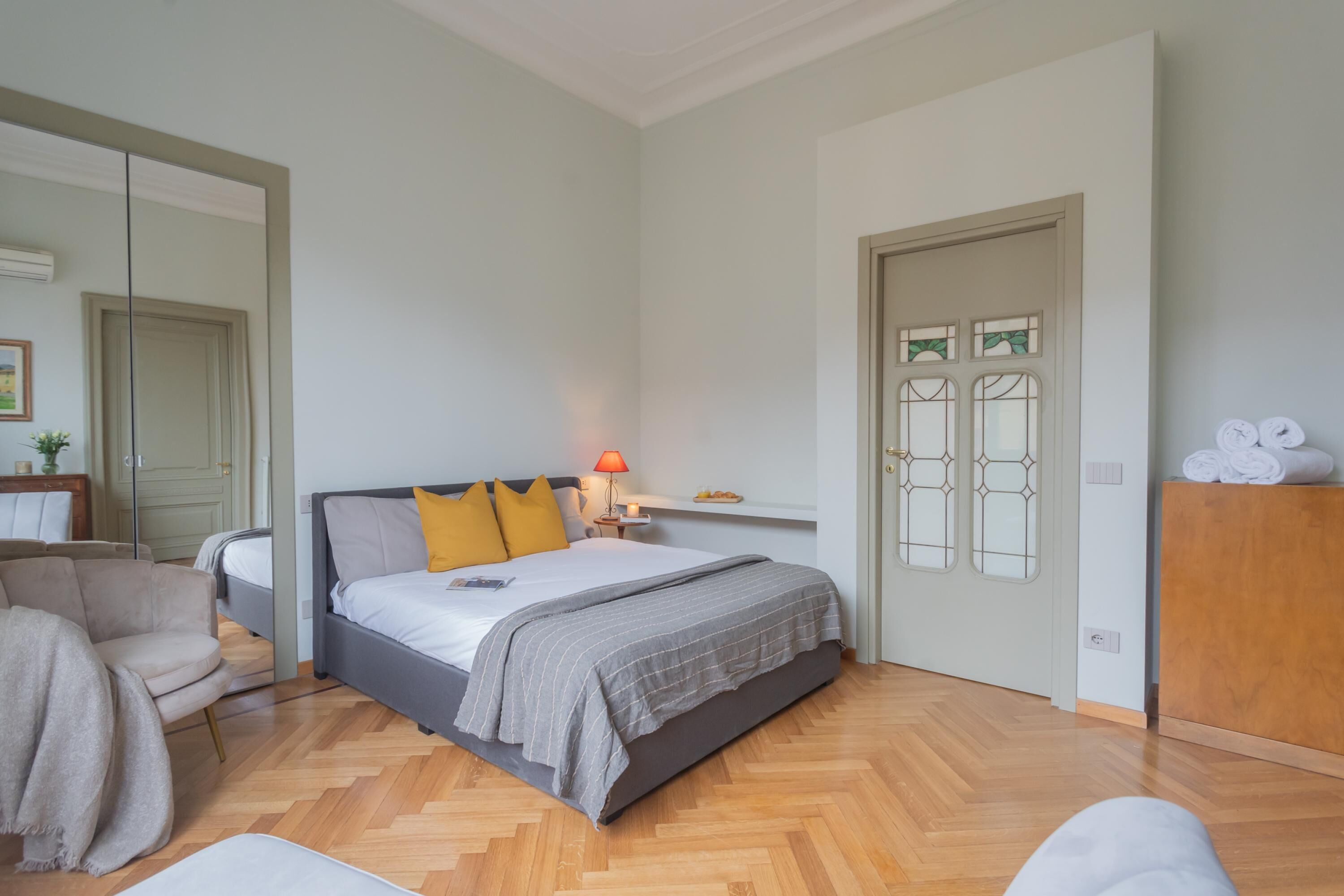 A bedroom with a bed, a chair, a nightstand, and a door with glass panels.