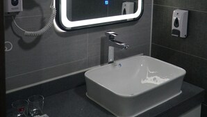 A bathroom with a modern sink, a hairdryer, and a hand soap dispenser. - Bayantsambagarav Hotel (Olgii)