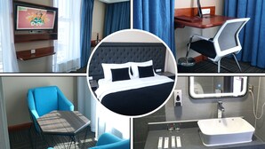 A hotel room with a bed, a desk, a chair, a TV, and a bathroom. - Bayantsambagarav Hotel (Olgii)