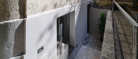 A staircase leading to a modern building with a stone facade and a metal railing.