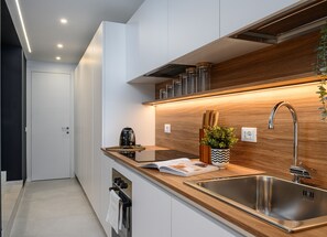 Uma cozinha moderna com pia de aço inoxidável, bancada de madeira e forno embutido.
