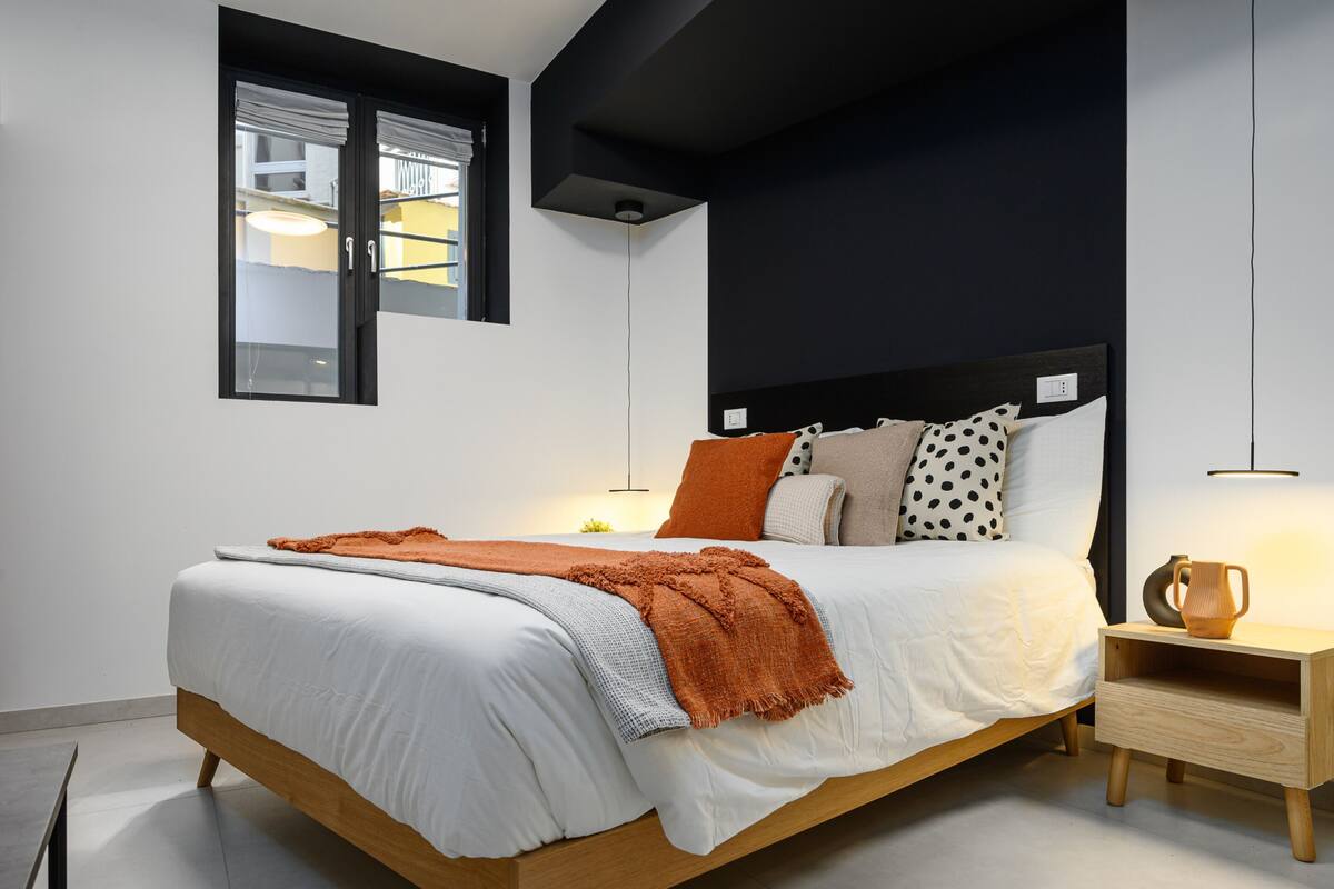 A modern bedroom with a wooden bed, white bedding, and a black headboard.