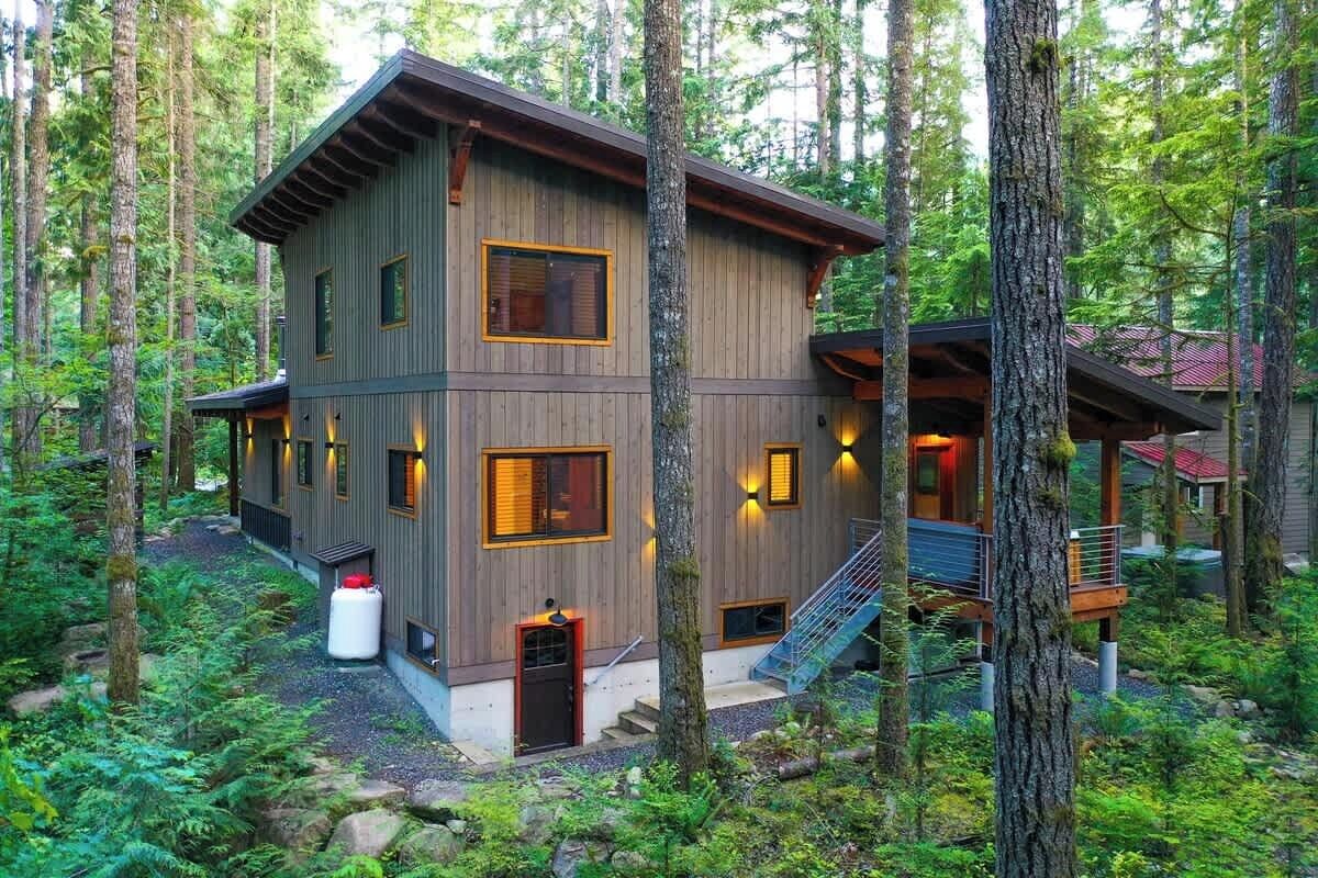 A multi-story wooden cabin surrounded by forest.