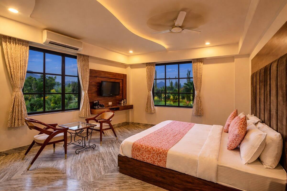 A hotel room with a bed, desk, chair, TV, and large windows.