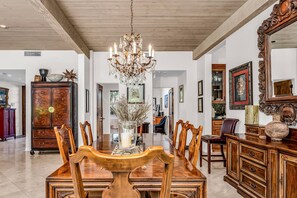 Enjoy meals in this elegant dining area with a large table and six chairs, a crystal chandelier, and beautiful artwork.