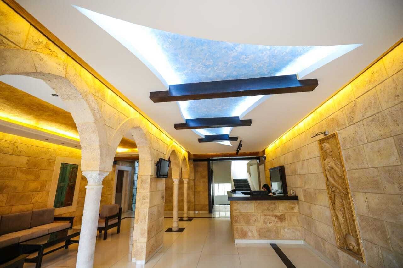 Un'area di accoglienza con lucernario, colonne in pietra, una reception e zone relax.