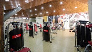 Un gimnasio con diferentes máquinas de ejercicio, techo de madera y carteles motivacionales en las paredes.