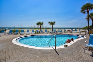 A swimming pool with lounge chairs and palm trees, overlooking a beach. - On the Beach Across From Johns Pass. Heated Pool. Spacious and Updated. (Madeira Beach)