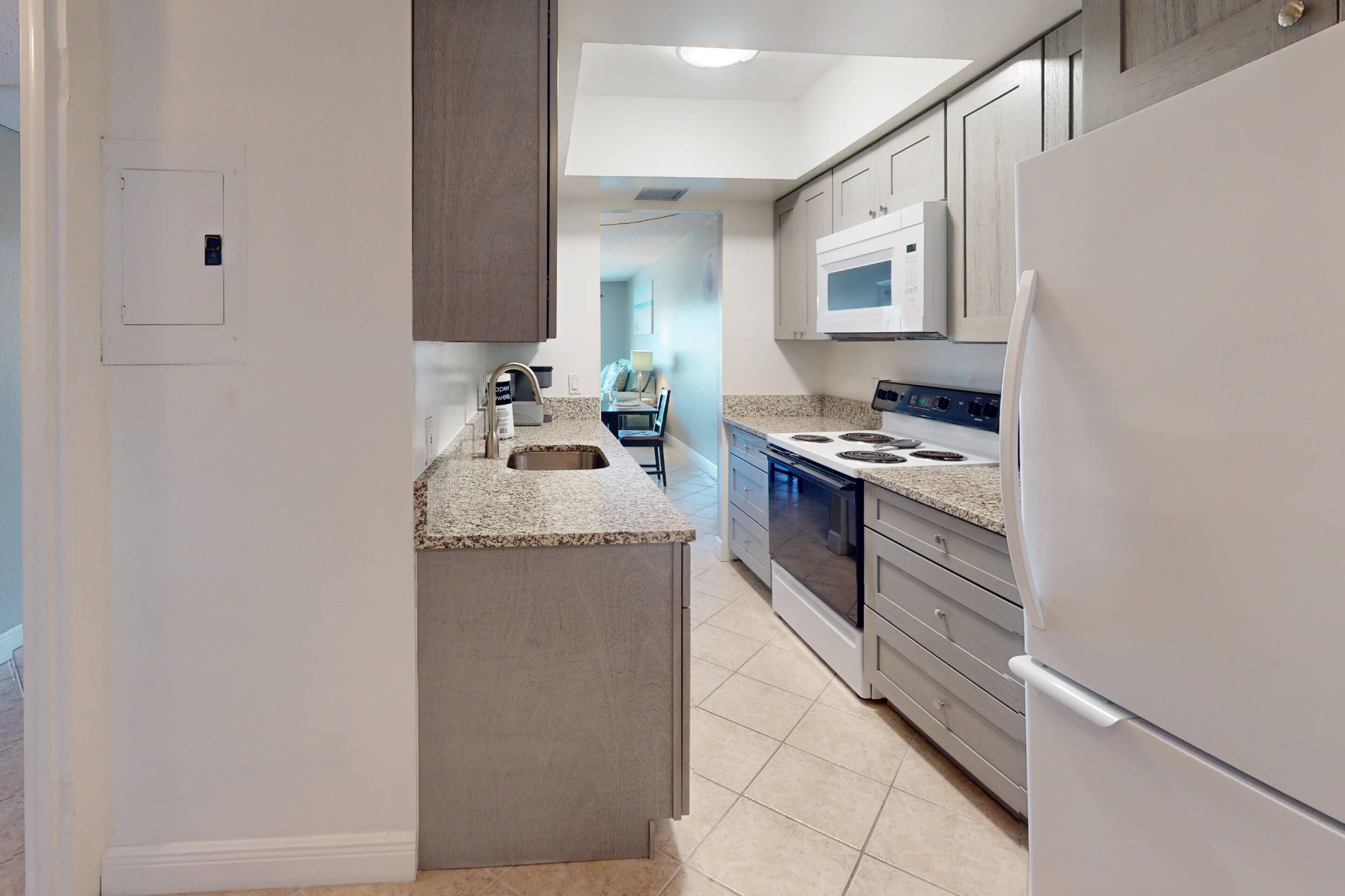 A modern kitchen with a central island, stainless steel appliances, and a view into the adjacent living area.