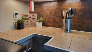 Eine Küche mit Holzrückwand, einer Spüle und einer Arbeitsplatte mit Pflanze und Kochgeschirr.
