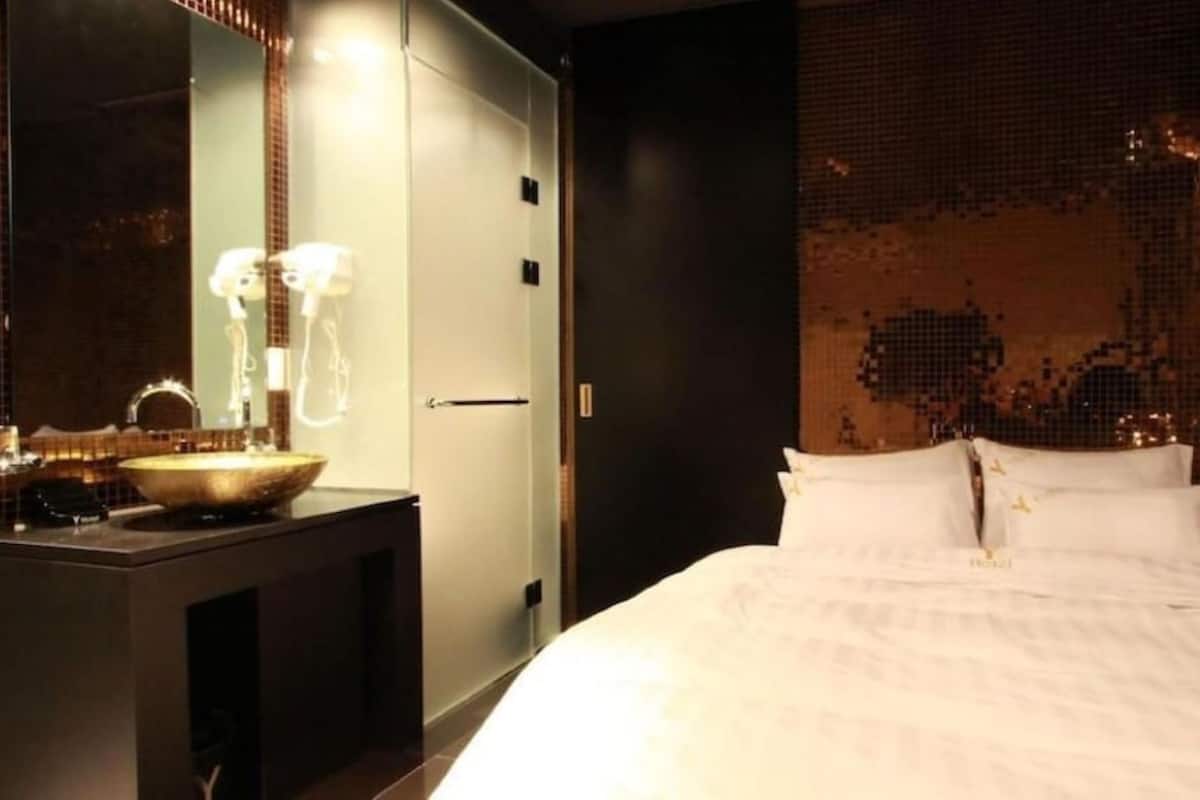 Habitació d'hotel amb un llit gran, una tocador amb un lavabo i un mirall.