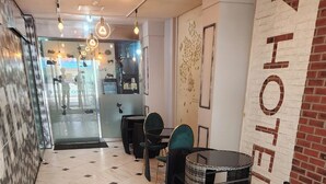 A hotel lobby with a stone-patterned floor, wicker furniture, and a 'HOTEL' sign on the wall. - sinchon Y hotel (Seoul)