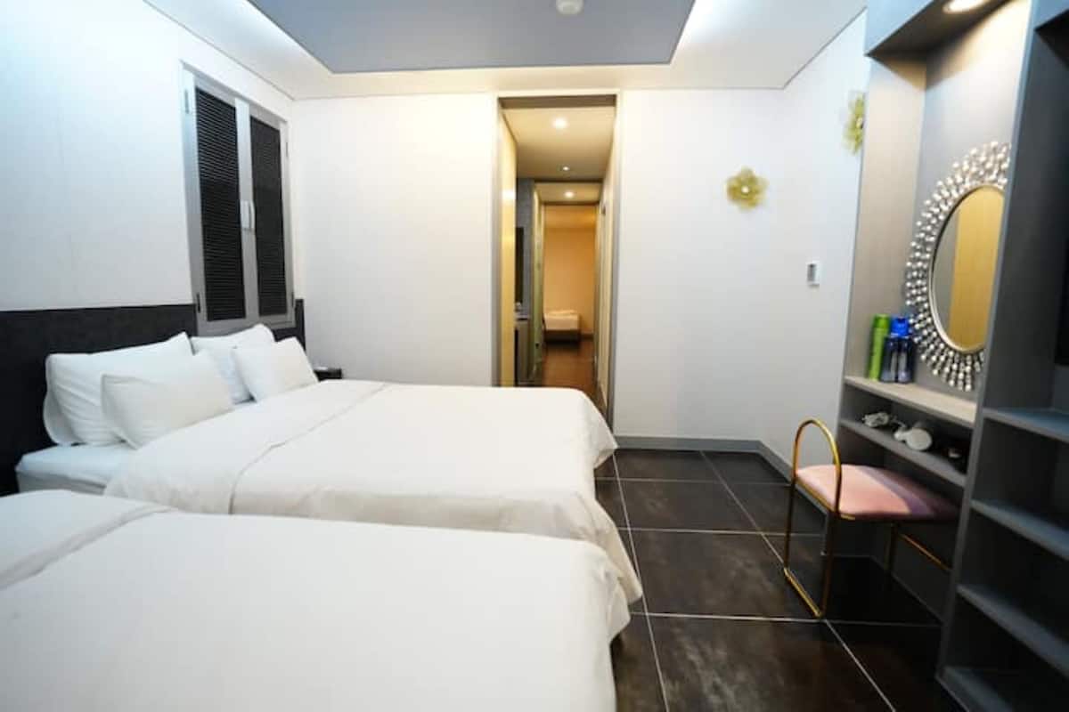 Habitació d'hotel amb dos llits, una tocador amb mirall i una petita zona de seients.
