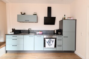 Eine moderne Küche mit hellblauen Schränken, einer schwarzen Dunstabzugshaube und einem Edelstahlbackofen.