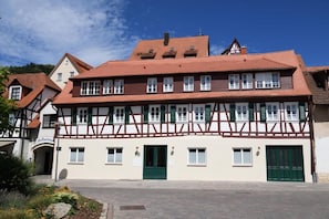 Un bâtiment traditionnel à colombages, doté de nombreuses fenêtres et d’une porte verte.